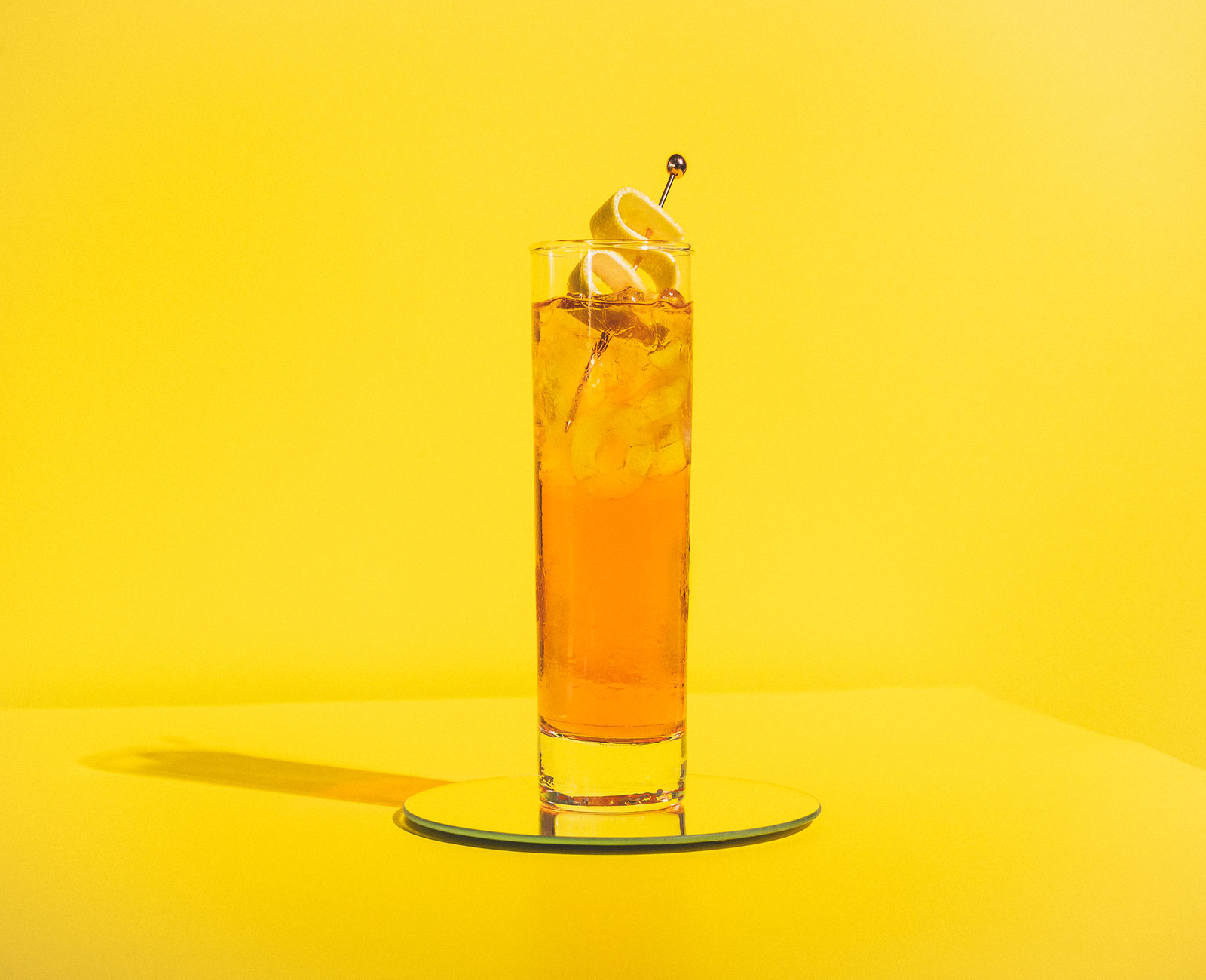Madera County Spritz aperitif with a grapefruit peel garnish and yellow background