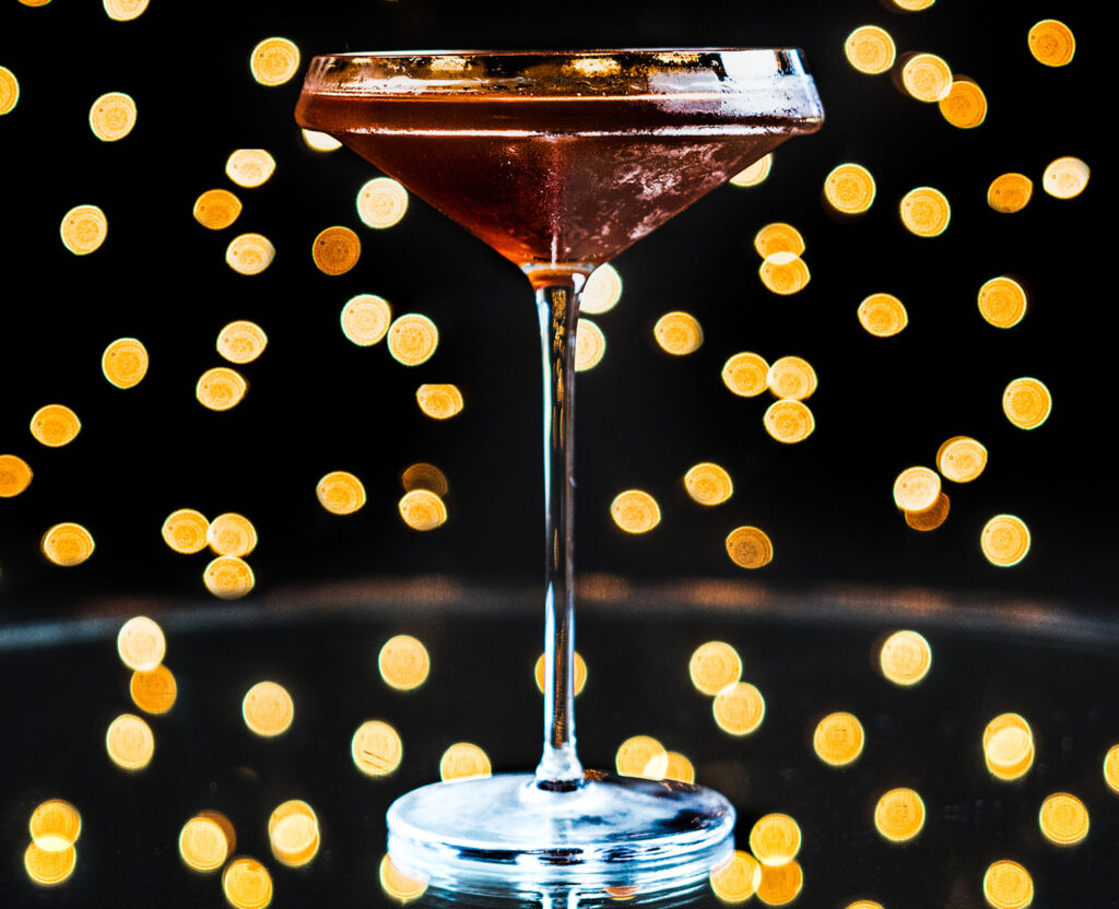 Midnight Manhattan cocktail with twinkle lights behind it