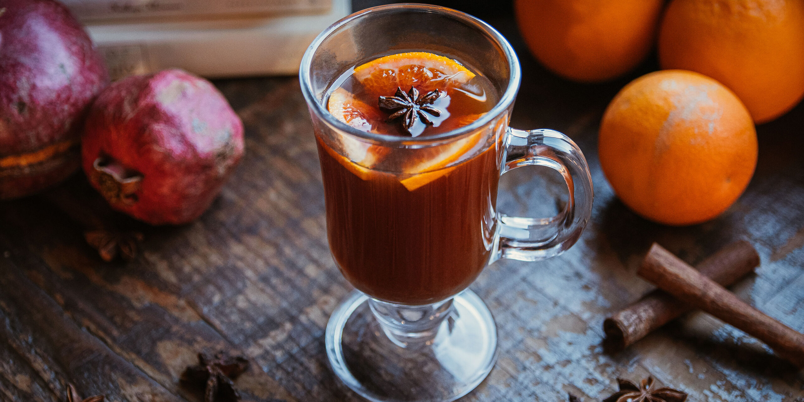 Mug of Mulled Vya with pomegranates and oranges and cinnamon sticks