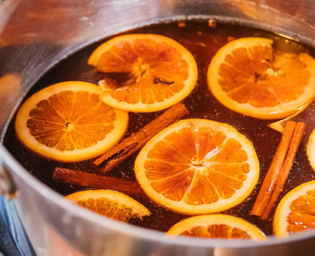 Pot of Mulled Vya with orange slices and cinnamon sticks