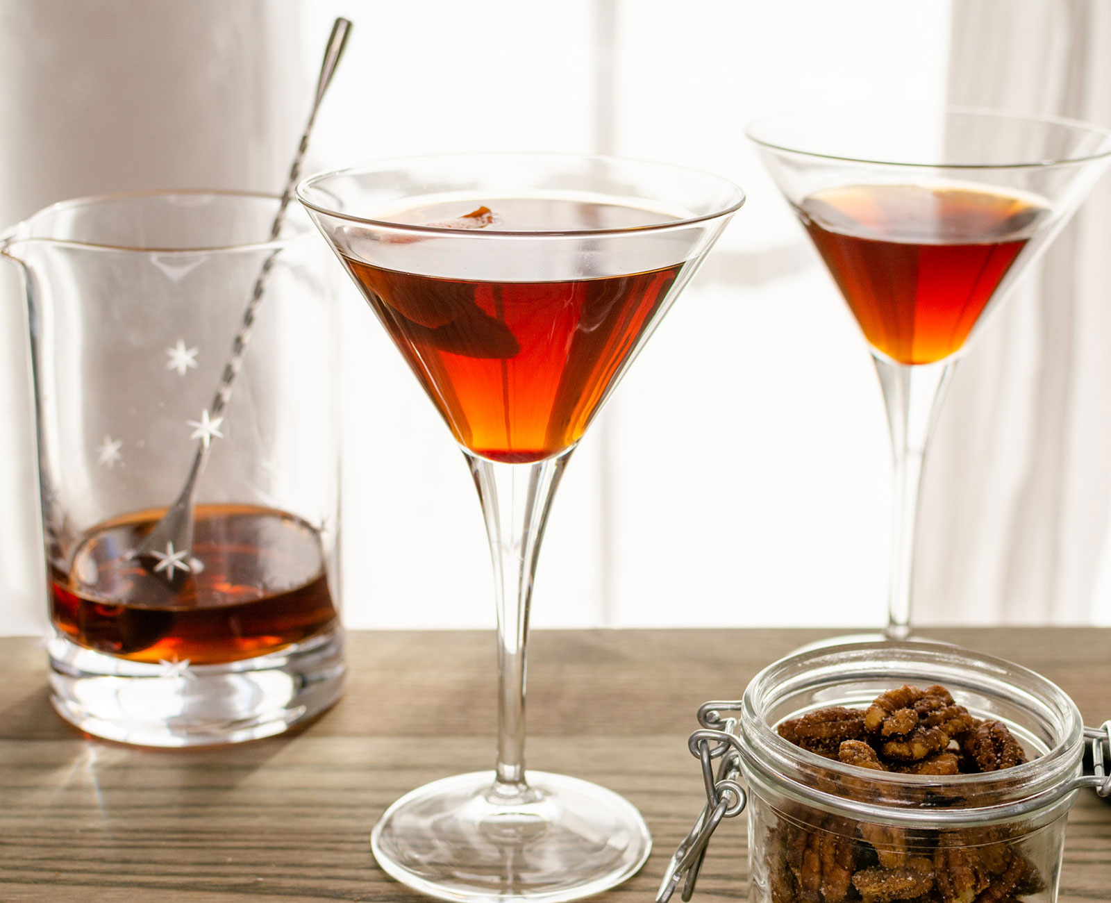 2 Pecan Pie Manhattans with a jar of candied pecans